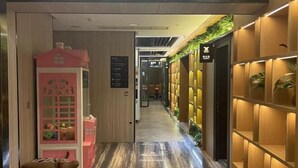 A hotel corridor with a wooden floor, a pink playhouse, and shelves with plants. - The Origin Hotel (Wenzhou Lucheng Road Guanghua Bridge) (Wenzhou)