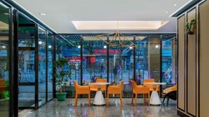 A modern dining area with glass walls, a central table, and orange chairs. - The Origin Hotel (Wenzhou Lucheng Road Guanghua Bridge) (Wenzhou)