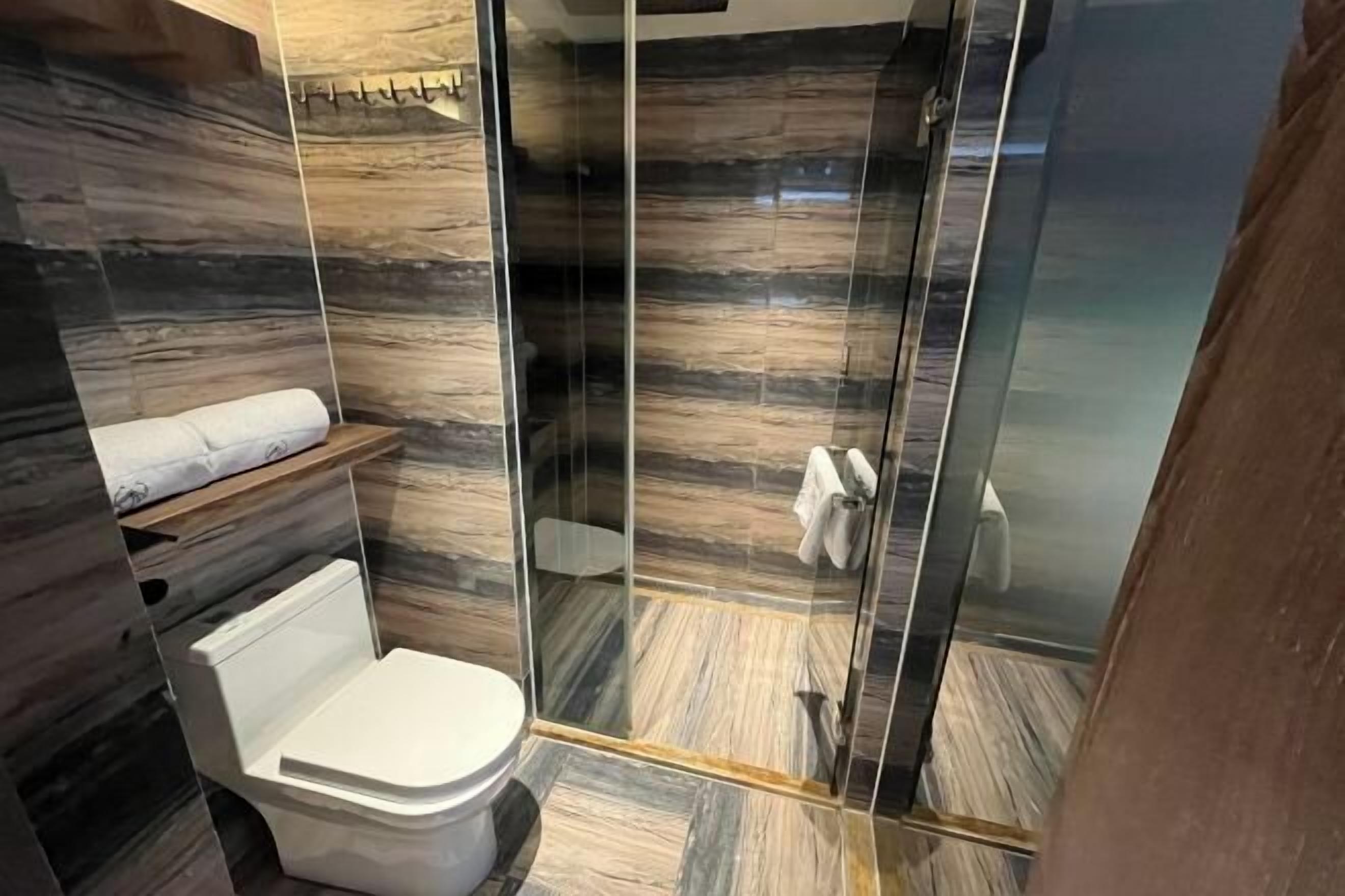 A modern bathroom with a glass-enclosed shower, a toilet, and a towel rack.