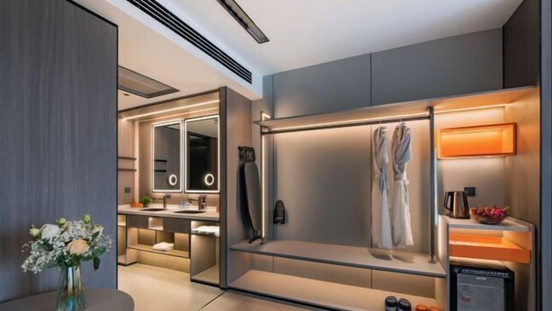 A modern hotel room with a walk-in closet, a vanity with a mirror, and a built-in shoe rack. - The Origin Hotel (Wenzhou Lucheng Road Guanghua Bridge) (Wenzhou)