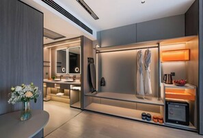 Une chambre d’hôtel moderne dotée d’un dressing, d’une coiffeuse avec miroir et d’un meuble à chaussures intégré.