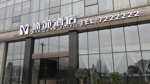 A modern hotel entrance with glass doors and potted plants. - Nanyuan Hotel (Jinsha)