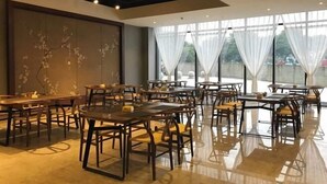 A spacious restaurant with multiple tables and chairs, large windows with sheer curtains, and a polished floor. - Nanyuan Hotel (Jinsha)