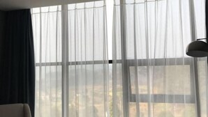 A room with a large window, a chair, and a lamp. - Nanyuan Hotel (Jinsha)
