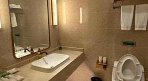 A bathroom with a bathtub, toilet, and a mirror.