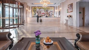 A spacious lobby with a grand chandelier, a reception desk, and a seating area with a vase of flowers. - Vienna International Hotel (Wuxi)