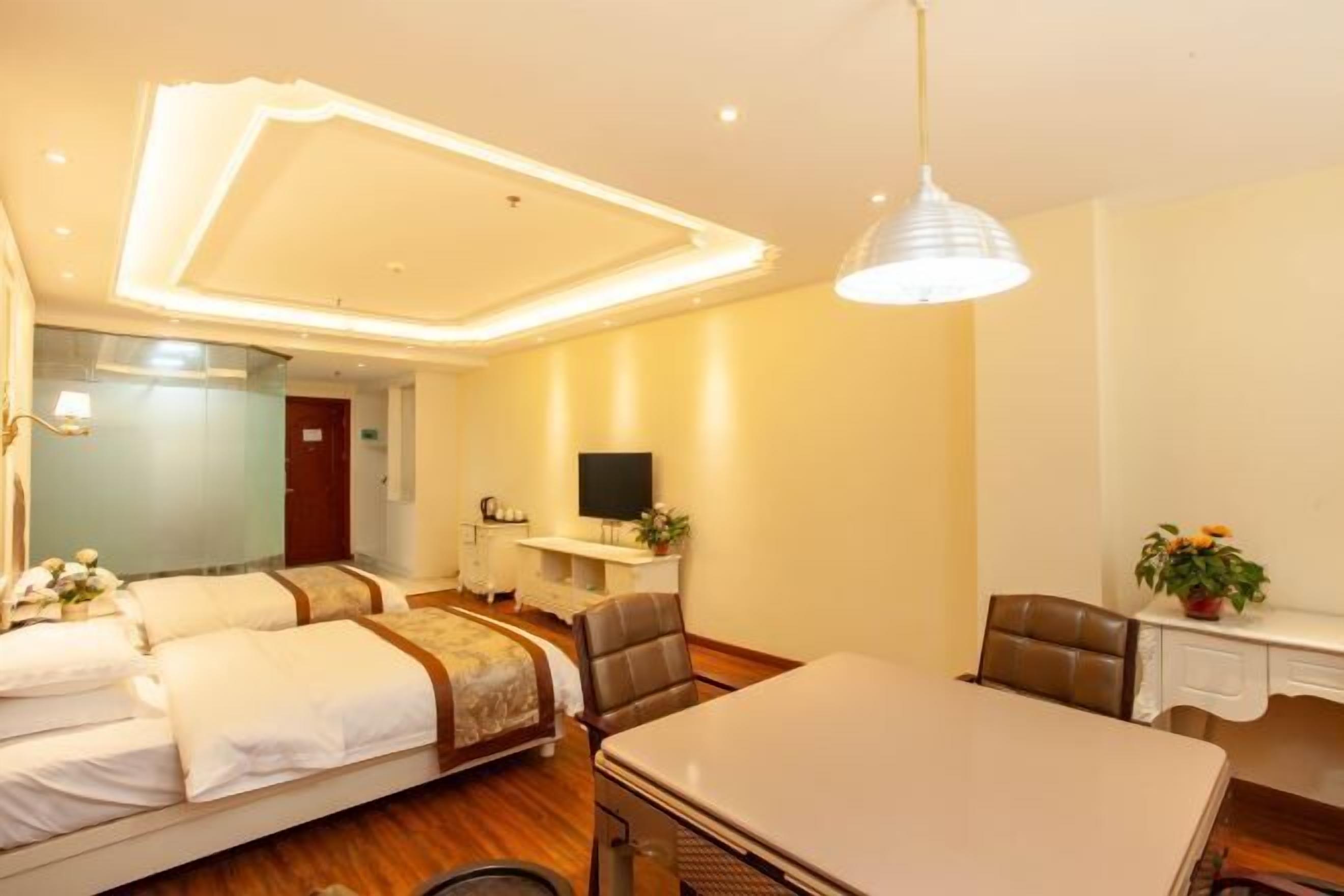 A hotel room with a bed, a desk, a chair, a television, and a plant.