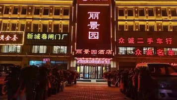 A hotel entrance with a prominent sign for "丽景园" and a row of parked cars in front.