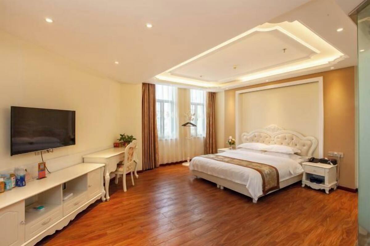 Una habitación de hotel moderna con una cama grande, un televisor montado en la pared, un escritorio y una silla.