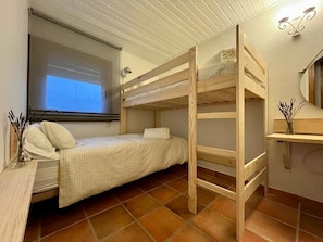 Compact room with a bunk bed, desk area, and window offering a view.