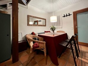 A compact living space with a dining area, a large mirror, and a small kitchen area. - Rural house The refuge of Lucas (La Adrada)