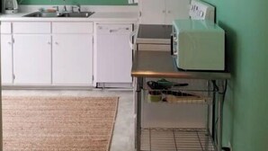 A kitchen with white cabinets, a sink, and a countertop with a coffee maker.