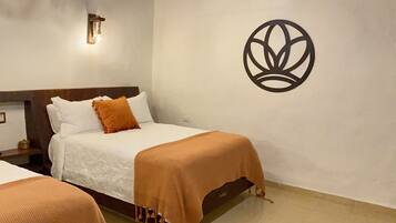 A hotel room with two beds, a wooden ceiling, and a wall-mounted light fixture.