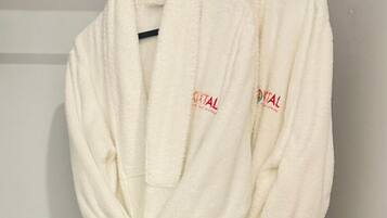 Two white bathrobes with red text hanging on a wooden hanger.
