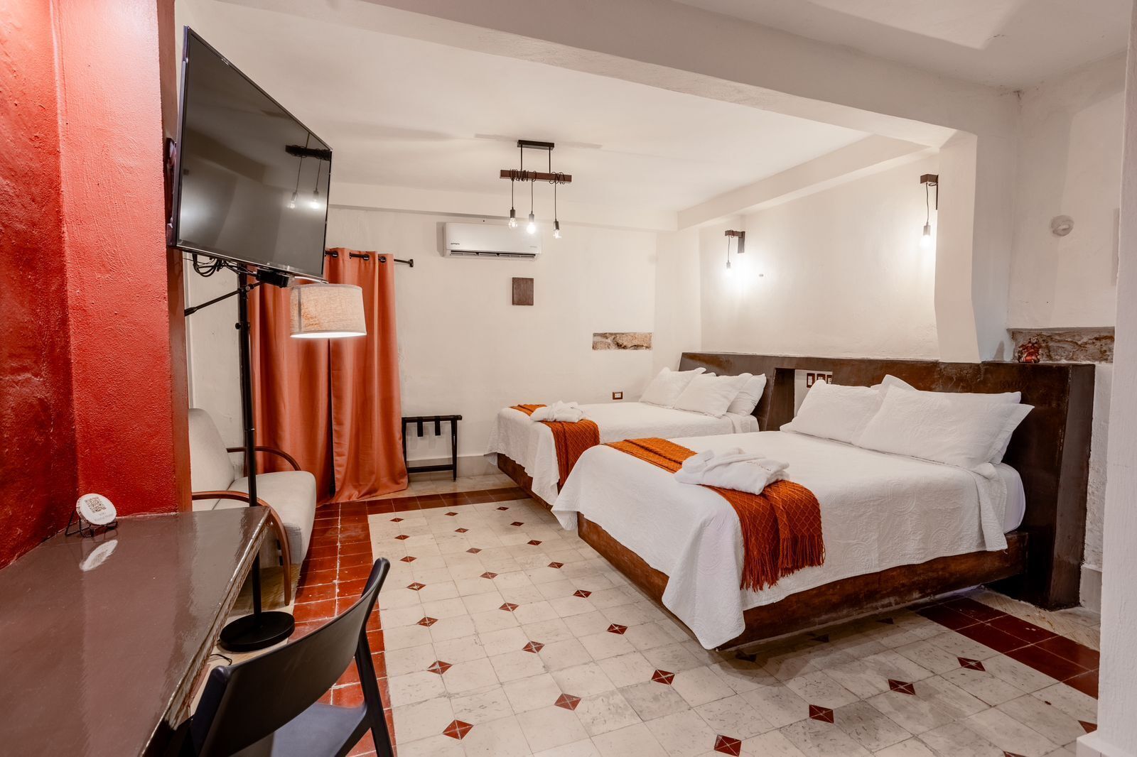 A hotel room with two beds, a desk, and a TV.