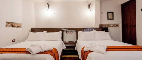 Une chambre d’hôtel avec deux lits, un petit bureau et une porte.