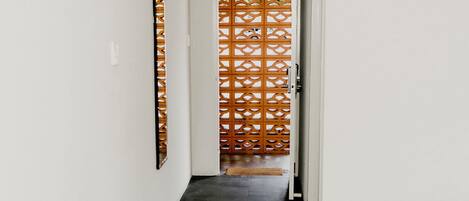 A hallway with a wooden lattice partition, a door, and a dark wooden floor.