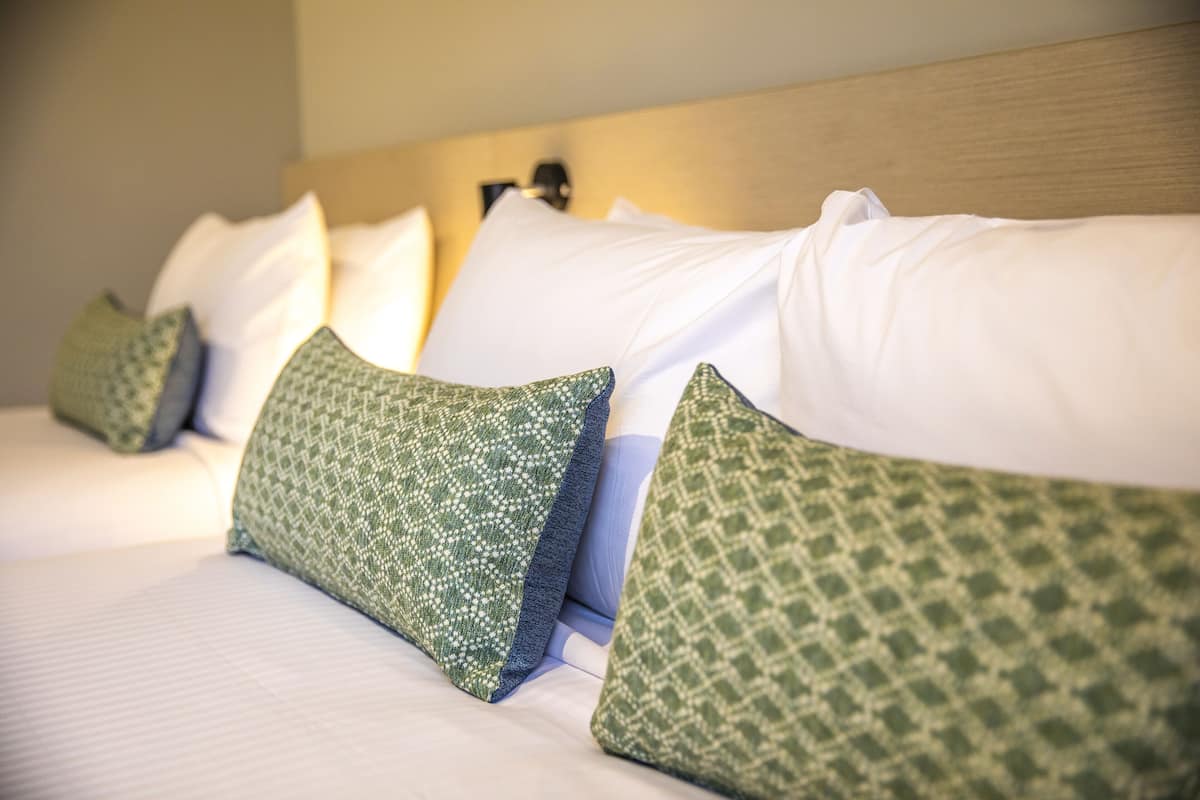 A neatly made bed with white and green patterned pillows.