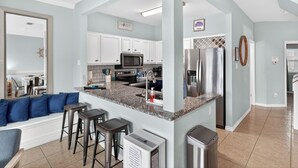 A modern kitchen with white cabinets, a granite countertop, stainless steel appliances, and a built-in island with bar stools. - Townhome on the water. Sleeps8. Pet friendly! (Corpus Christi)