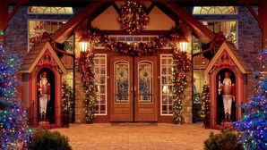 A building with a brick facade, a wooden entrance with a large door, and two small towers with nutcracker statues.