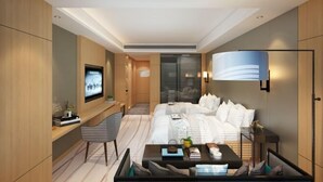 Ett modernt hotellrum med en säng, ett skrivbord, en stol, en TV och en lampa.