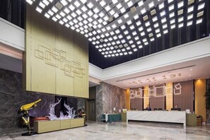 A spacious lobby with a high ceiling, a reception desk, and a decorative wall. - New Beacon International Hotel (Enshi Cultural Center) (Enshi City)