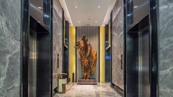 Un interior moderno con piso de mármol, una escultura central y un letrero azul.