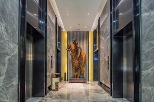 Un interior moderno con piso de mármol, una escultura central y un letrero azul.