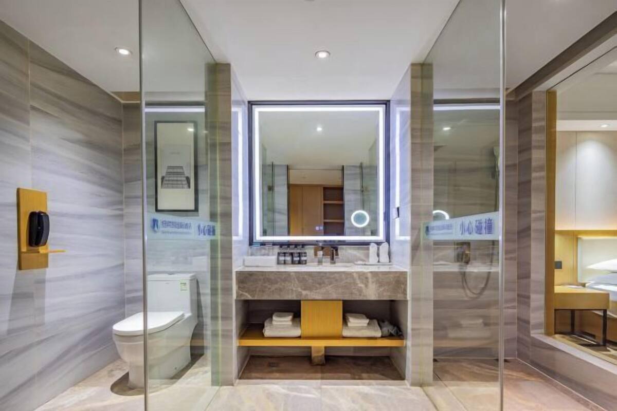 Un baño moderno con ducha de vidrio, lavamanos de mármol y un espejo grande.