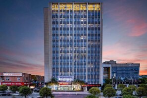 A high-rise building with multiple floors, large windows, and a prominent sign at the top. - New Beacon International Hotel (Enshi Cultural Center) (Enshi City)