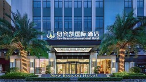 Det moderna New Beacon International Hotel har en tilltalande fasad med en framträdande entré och palmer.