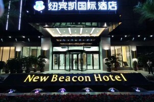 The exterior of the New Beacon Hotel with a prominent entrance, a glass facade, and a sign indicating the hotel's name.