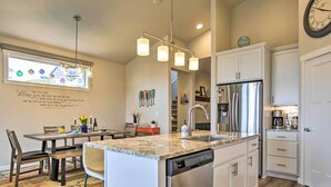A modern kitchen with a central island, stainless steel appliances, and a dining area with a view. - Stunning Neskowin Gem: View of Cascade Head! (Neskowin)