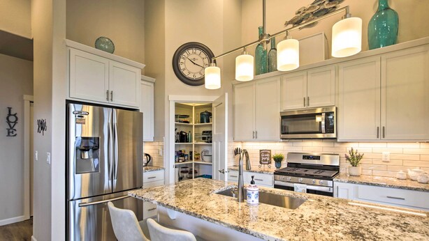 A modern kitchen with white cabinets, stainless steel appliances, a granite countertop, and bar stools. - Stunning Neskowin Gem: View of Cascade Head! (Neskowin)