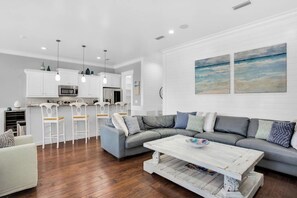 A modern kitchen with white cabinets, a grey sofa, and a coffee table. - Large 4 bedroom with bunk room and 2 golf carts! (Miramar Beach)