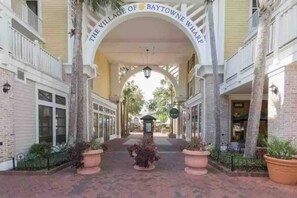 Een overdekte doorgang met een bord waarop 'The Village of Baytowne Wharf' staat, leidt naar een gebouw met een zichtbare koffiebar.