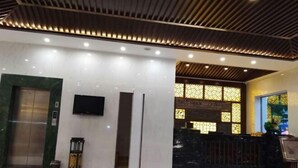 Un lobby moderno con una recepción, un televisor y una ventana con diseño.