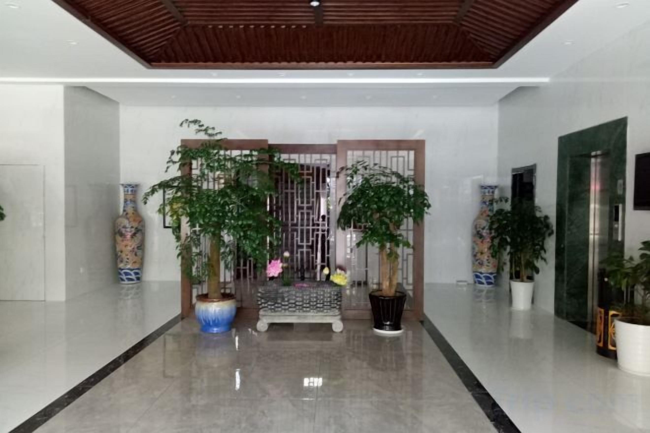 Een moderne lobby met een gepolijste vloer, een houten plafond en potplanten.