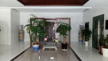 A modern lobby with a polished floor, a wooden ceiling, and potted plants.