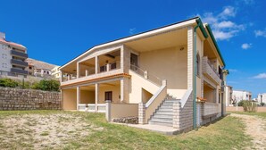 Un bâtiment à deux étages doté d’un balcon, d’un mur en pierre et d’un escalier menant à l’étage supérieur.
