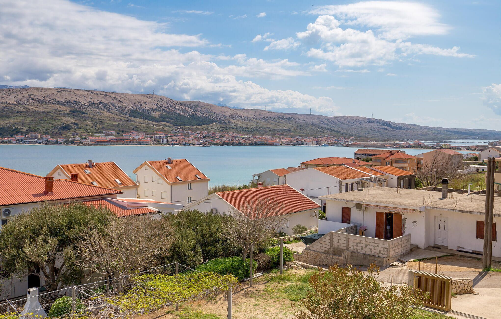 Un village côtier aux maisons aux toits de tuiles rouges, offrant une vue dégagée sur la mer et s’étendant sur un paysage vallonné.