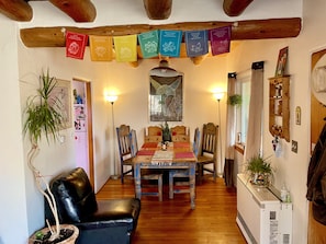 A cozy dining area with a wooden table and chairs, surrounded by wooden beams and a string of colorful cards. - Peaceful Home (Santa Fe)