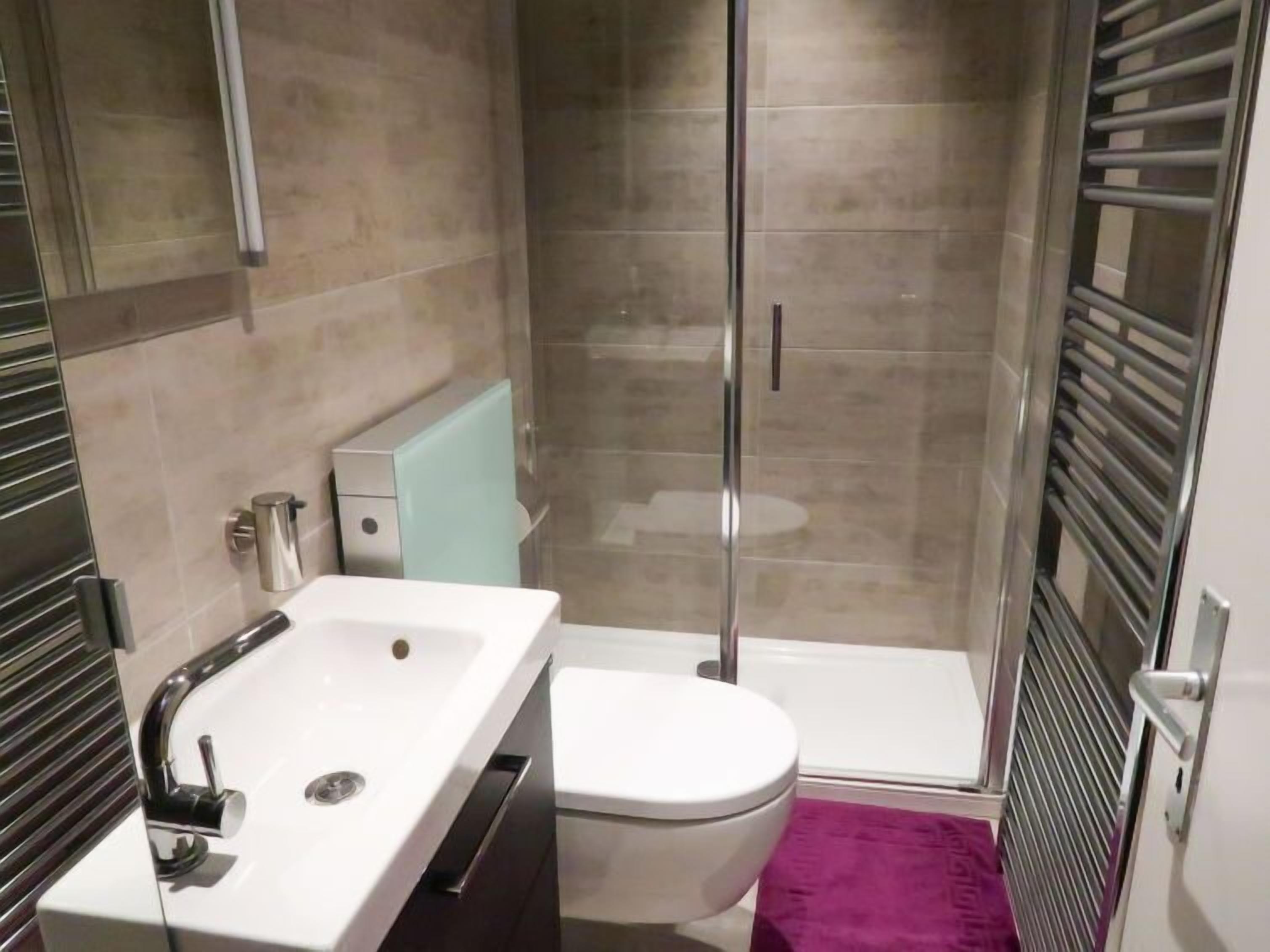 Een moderne badkamer met douche, toilet en wastafel.