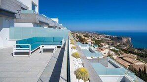 Une terrasse sur le toit avec un espace lounge moderne, une piscine et une vue sur la côte.