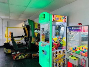 Un salón de juegos con varias máquinas, incluyendo un simulador de carreras y máquinas de garra.