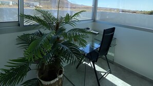 Una habitación moderna con ventanas amplias, una mesa de vidrio, una silla y una planta en maceta.