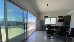 Una cocina moderna con comedor, grandes puertas de vidrio correderas y vista a un jardín ajardinado.