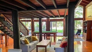 A spacious indoor area with a pool table, sofas, and a staircase.