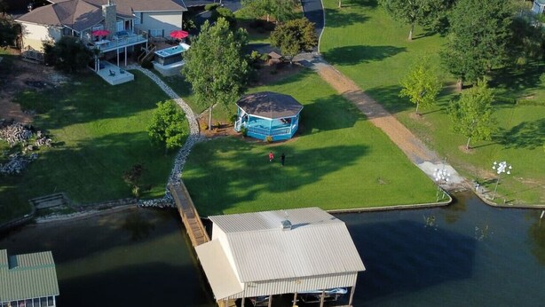 Vista aérea de una propiedad junto al lago, con muelle, un pabellón y una casa con piscina.