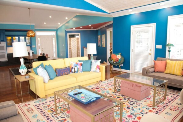 A living room with a yellow sofa, a glass coffee table, and a patterned rug.
